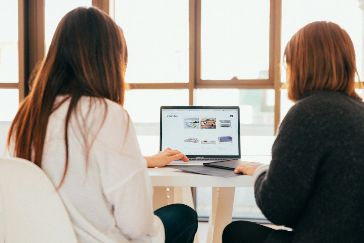 Two people reviewing a laptop near a window